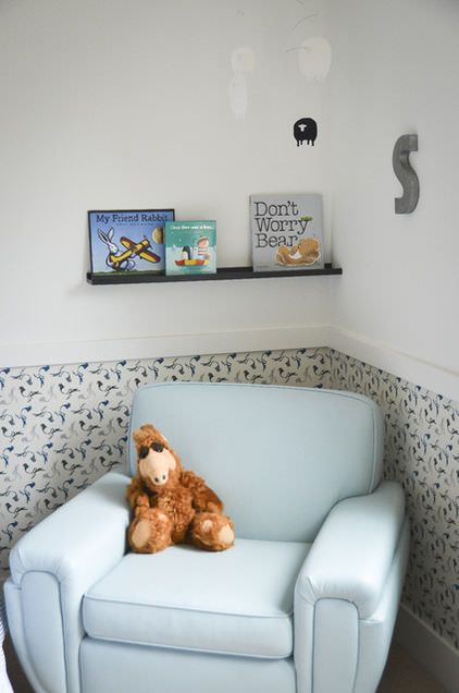 اتاق خواب کودکی که دارای مبل تک نفره آبی است و نیمی از دیوار آن رنگ و نیم دیگری از آن کاغذ دیواری شده است